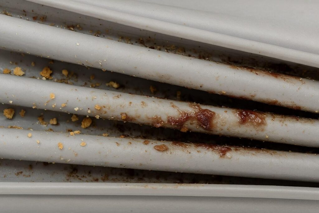 Close up of a dirty refrigerator door gasket filled with crumbs and sticky residue causing the door not to close.