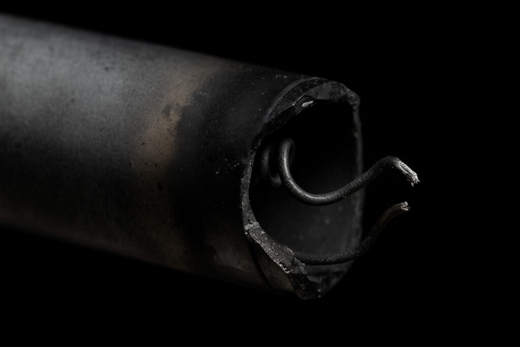 A broken glass tube heater showing black soot, a visual sign that you need to know how to test refrigerator defrost heater.