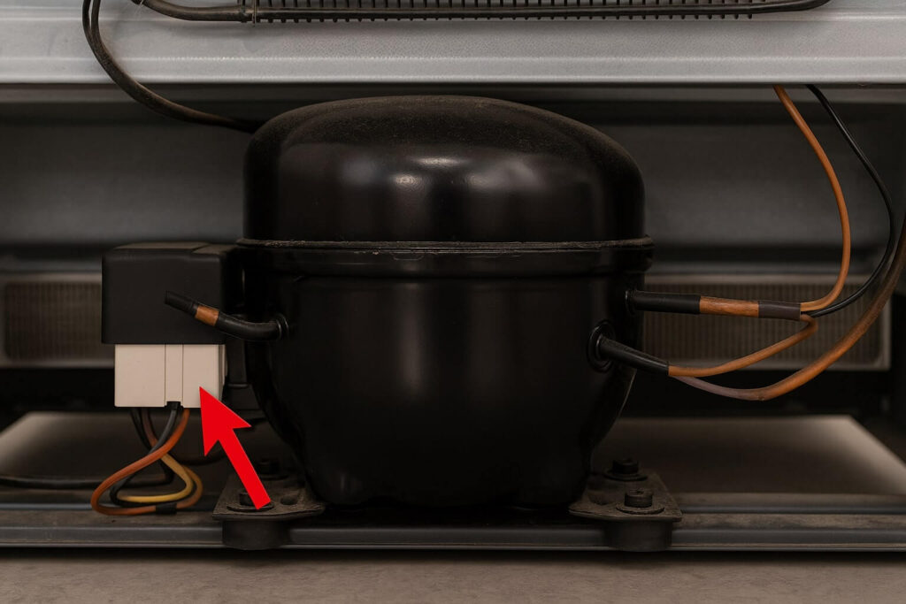 The location of the starter relay attached to the side of a black refrigerator compressor.