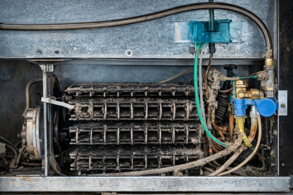 Thick dust buildup on refrigerator condenser coils causing compressor overheating
