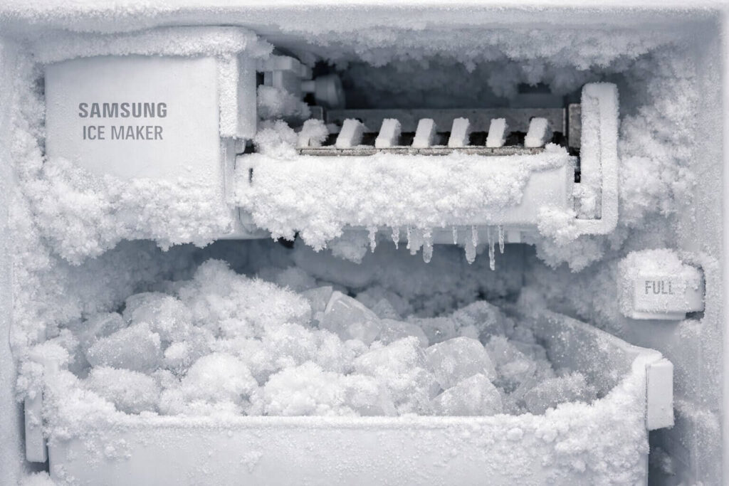 Close up of a Samsung refrigerator ice maker freezing up with heavy white frost covering the internal ice room.